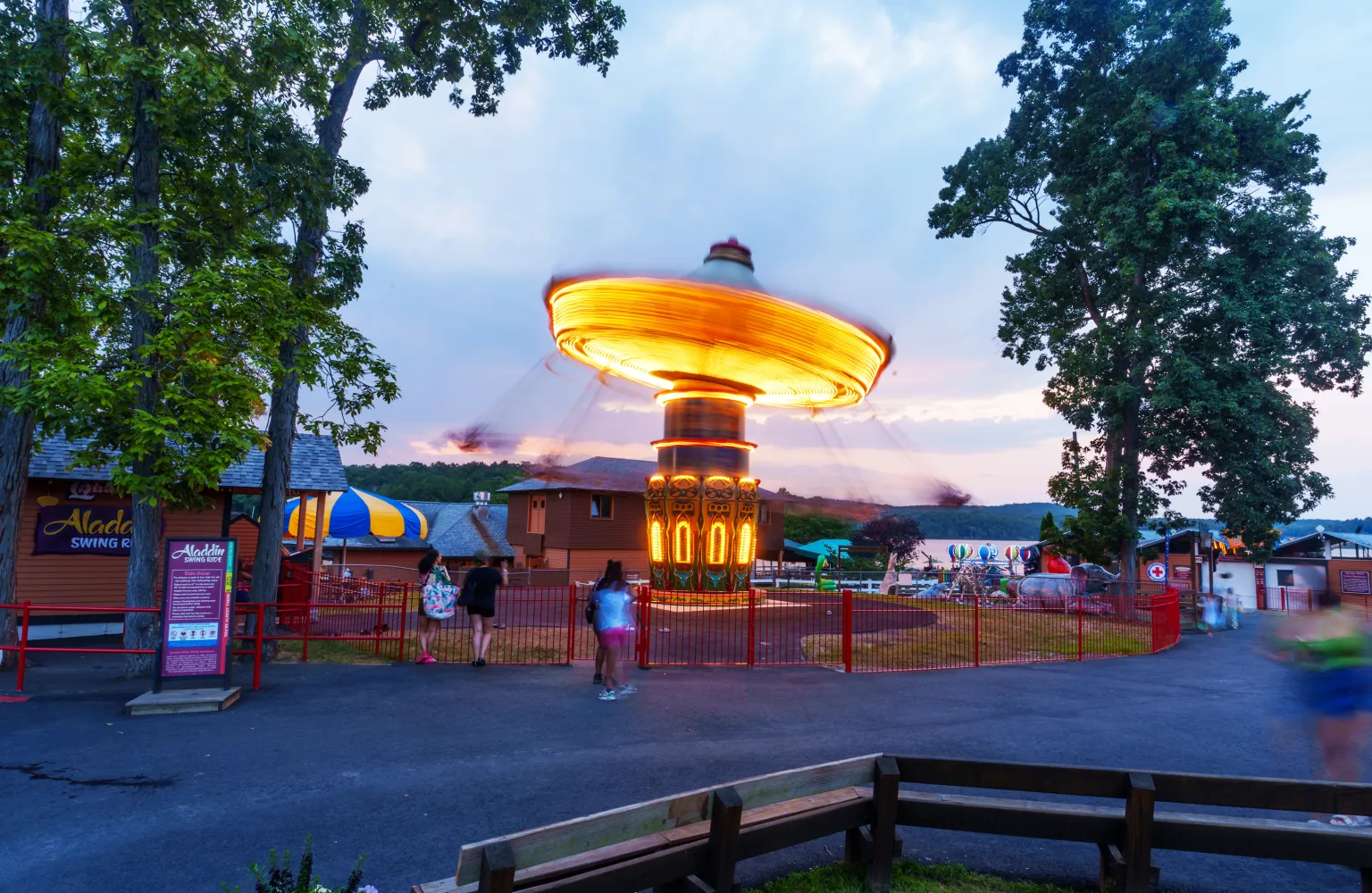 Spinning ride lit up with lights during dusk and sunset in background