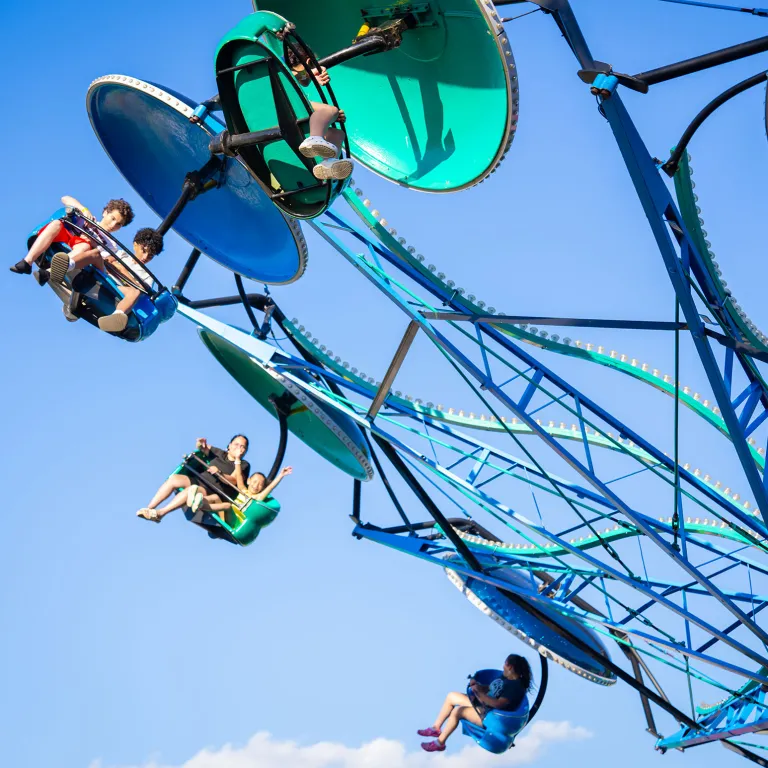 Adults and children riding on Paratroopers ride with sky in background