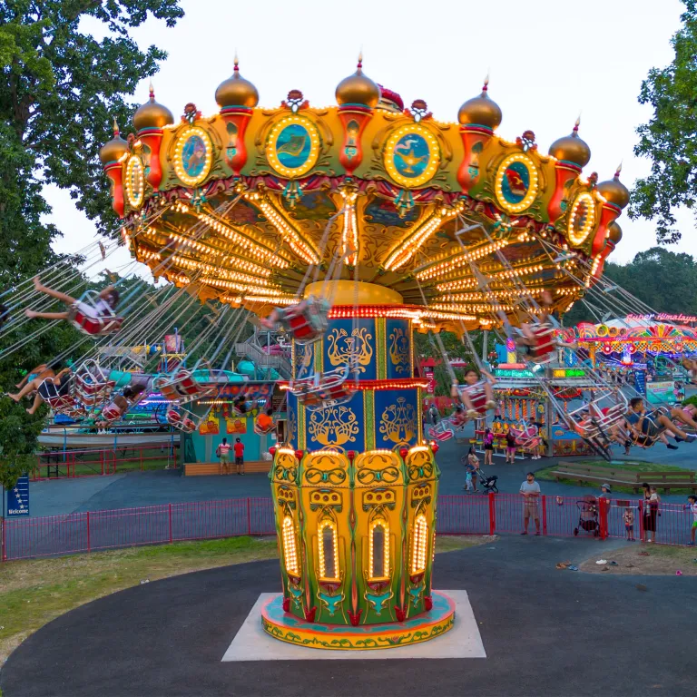 People sitting in chairs of the Aladdin Wave Swinger ride, spinning